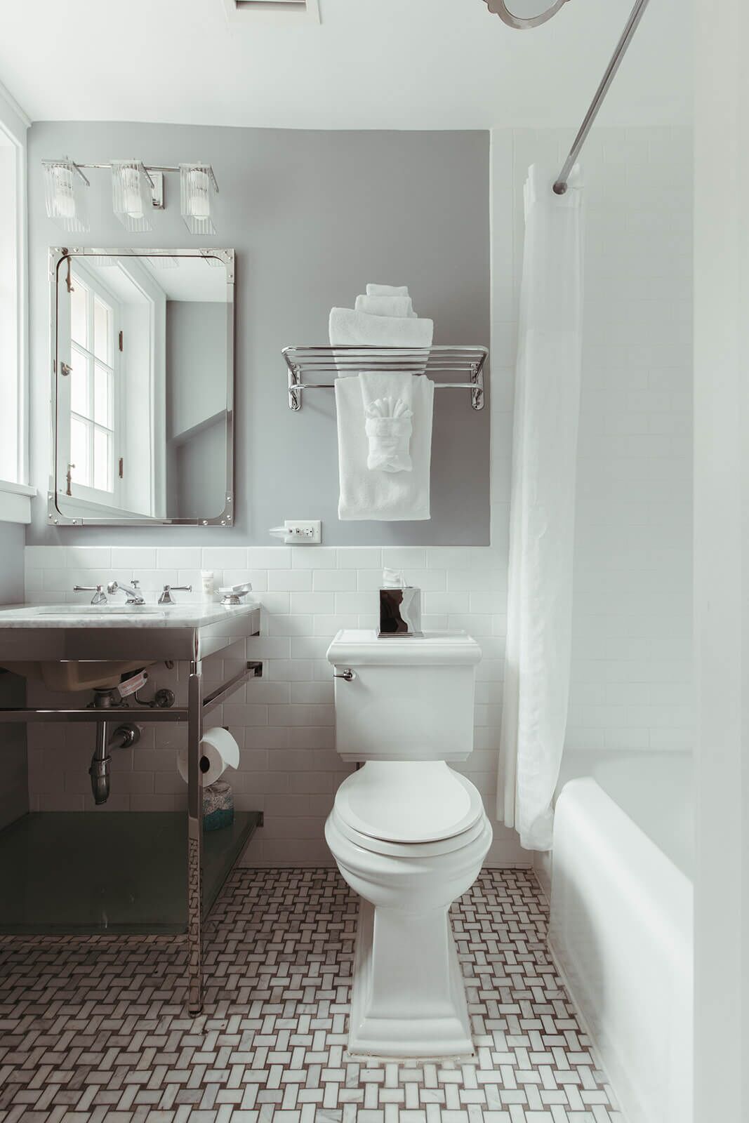 A modern bathroom with a white toilet, a sink with a mirror, and a towel rack.