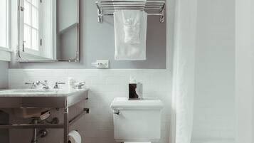 A modern bathroom with a white toilet, a sink with a mirror, and a towel rack.