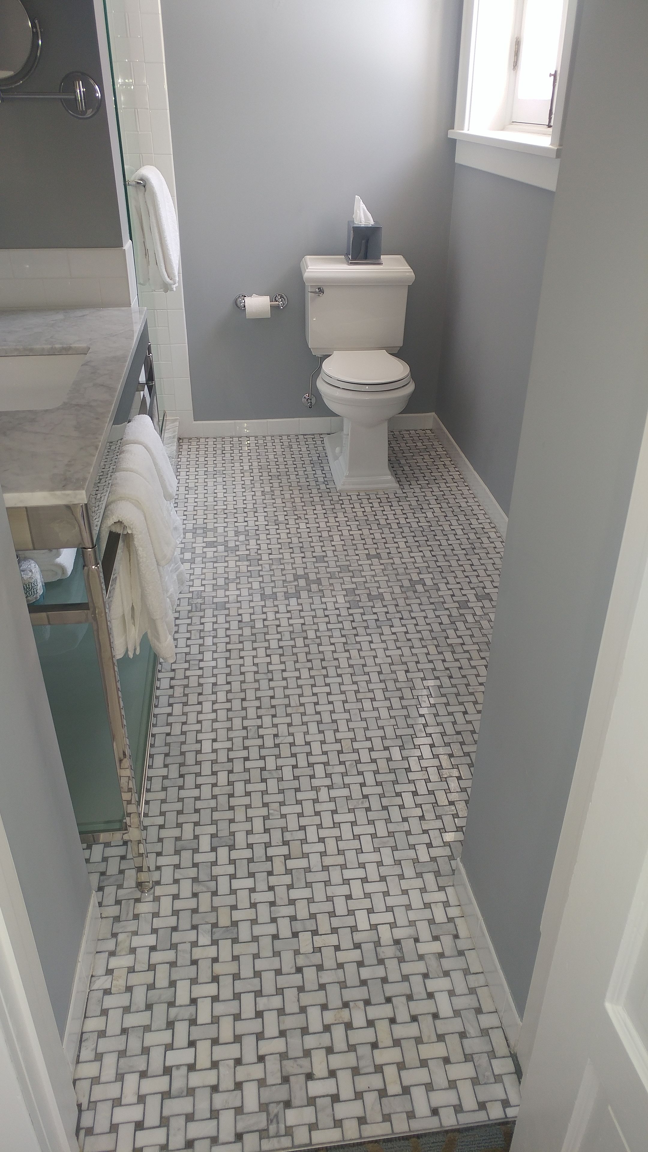 Et badeværelse med toilet, håndklædetørre og flisegulv.