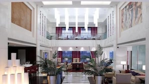 A spacious lobby with a central staircase, high ceilings, and a mezzanine level. - Dia Park Premier (Gurugram)