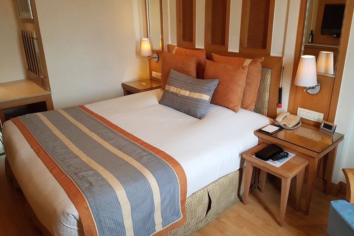 Habitación de hotel con una cama grande, dos mesitas de noche, un teléfono y una televisión.