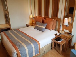 A hotel room with a large bed, two bedside tables, a telephone, and a TV.