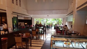 A hotel lobby with a reception desk, seating area, and a dessert display. - Dia Park Premier (Gurugram)