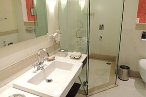 Un baño moderno con un espejo grande, dos lavamanos, cabina de ducha de vidrio y un inodoro.