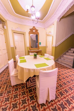 Un salón de conferencias con una mesa redonda, sillas blancas y una araña de cristal.