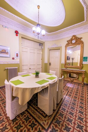 Un comedor con una mesa redonda, sillas, una araña y un suelo estampado.