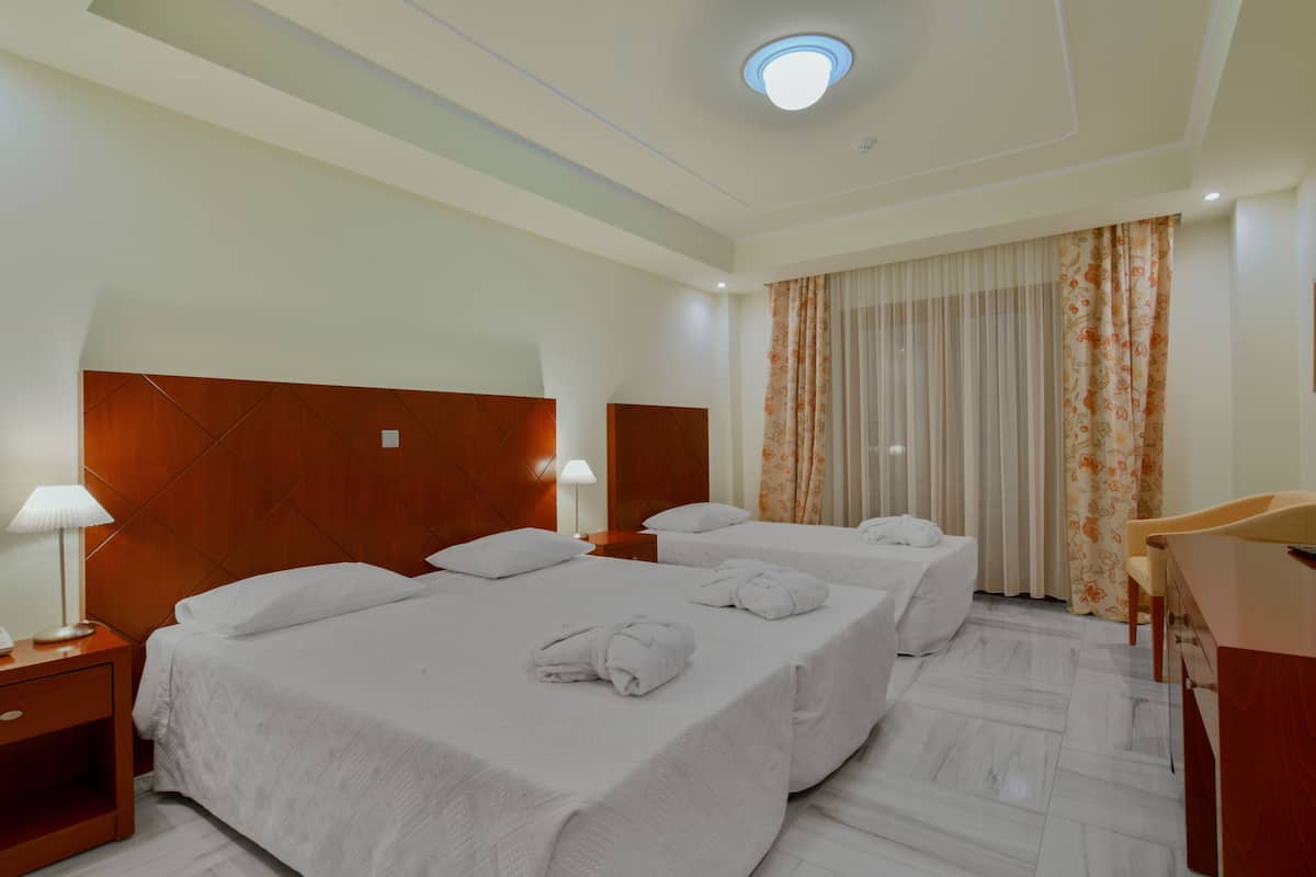 A hotel room with two beds, a desk, and a chair.