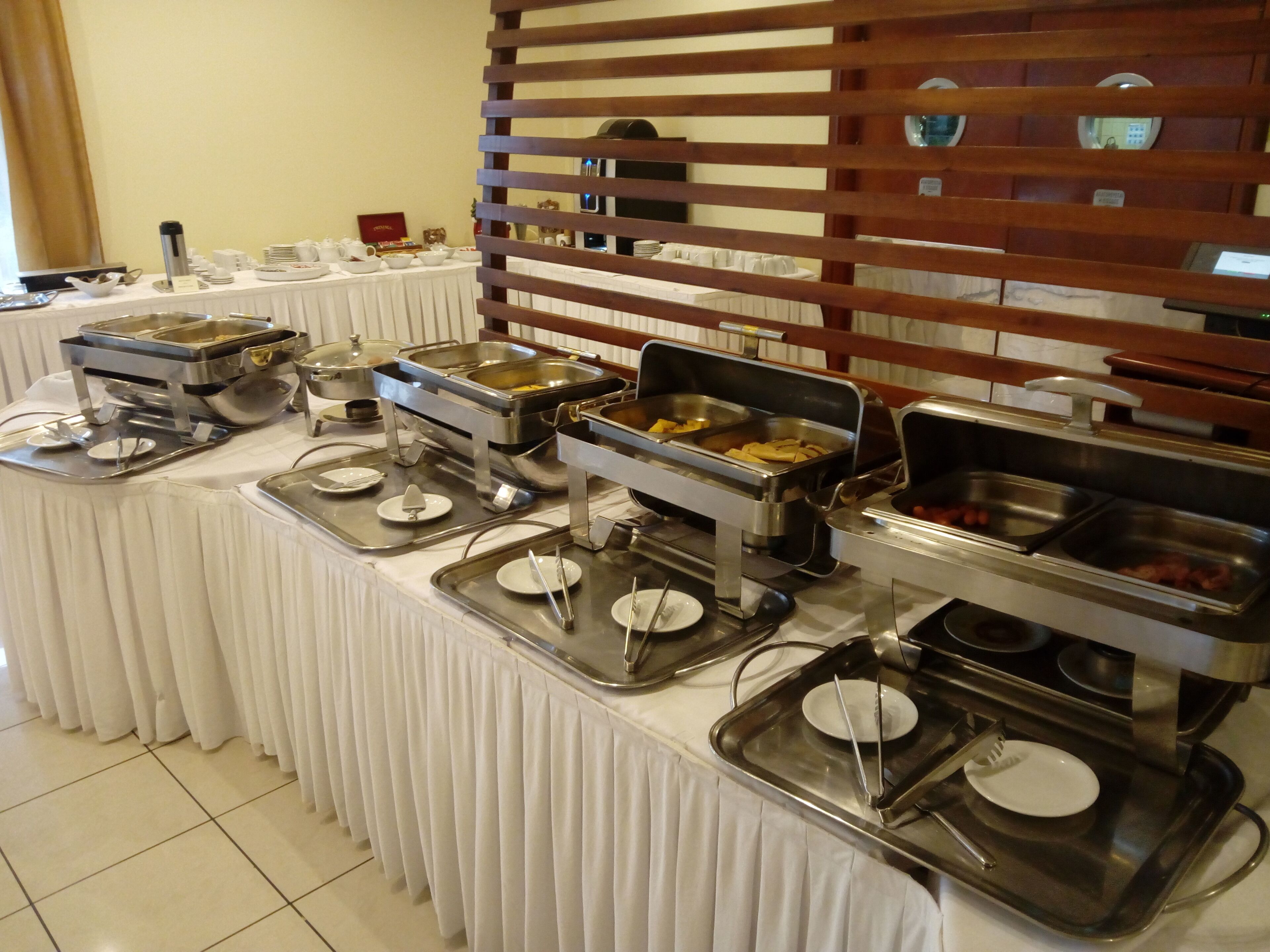 Ein Buffet mit verschiedenen Speisenstationen, darunter warme und kalte Speisen, präsentiert auf einem Tisch mit weißer Tischdecke.