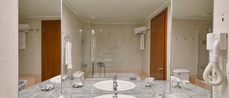 Un baño moderno con un espejo grande, dos lavamanos, una ducha e inodoro.