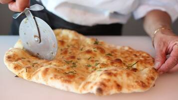 Une personne qui découpe une galette de pain à l’aide d’un coupe-pizza.