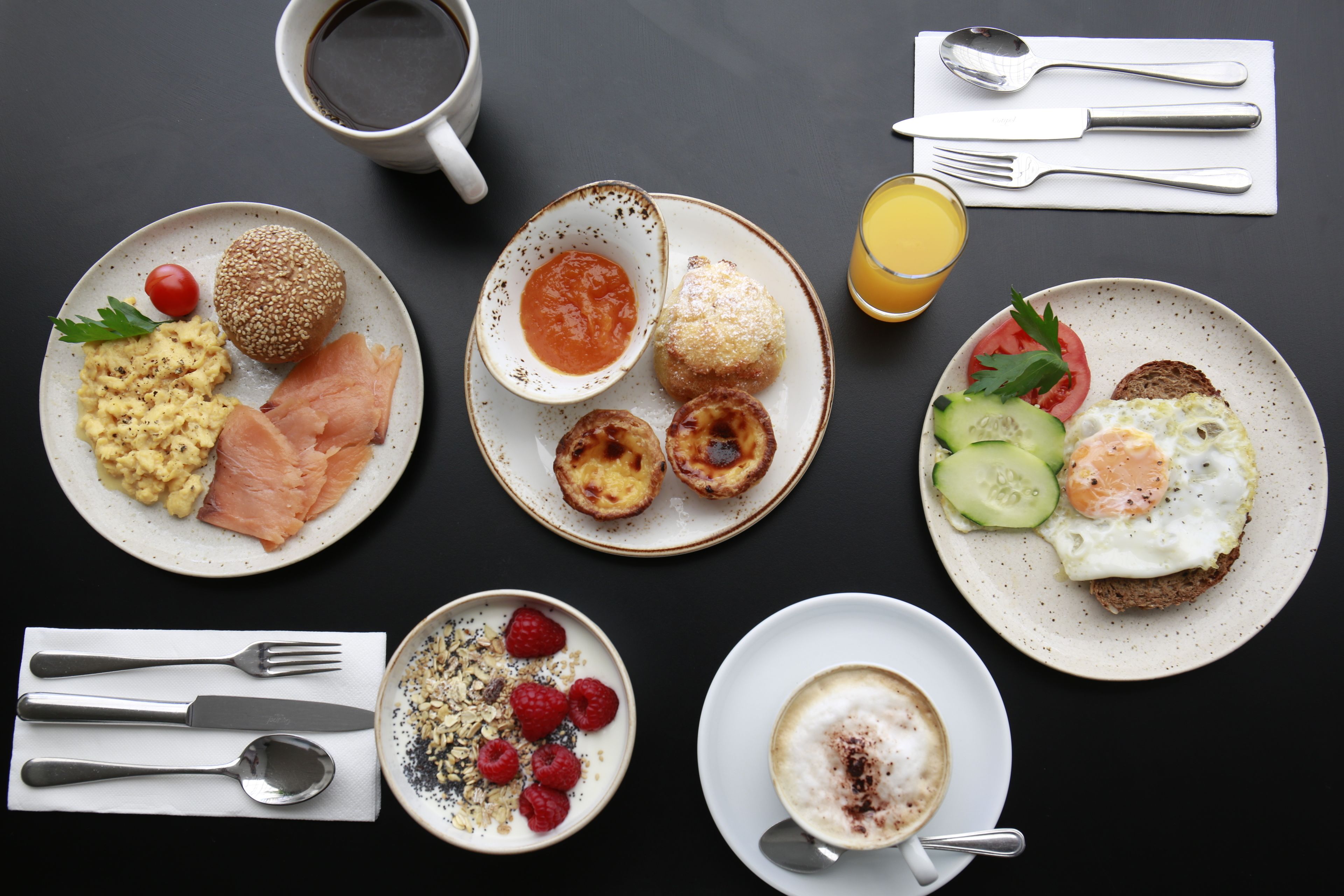 Ein Frühstückstisch mit Speisen, Geschirr und einer Kaffeetasse.