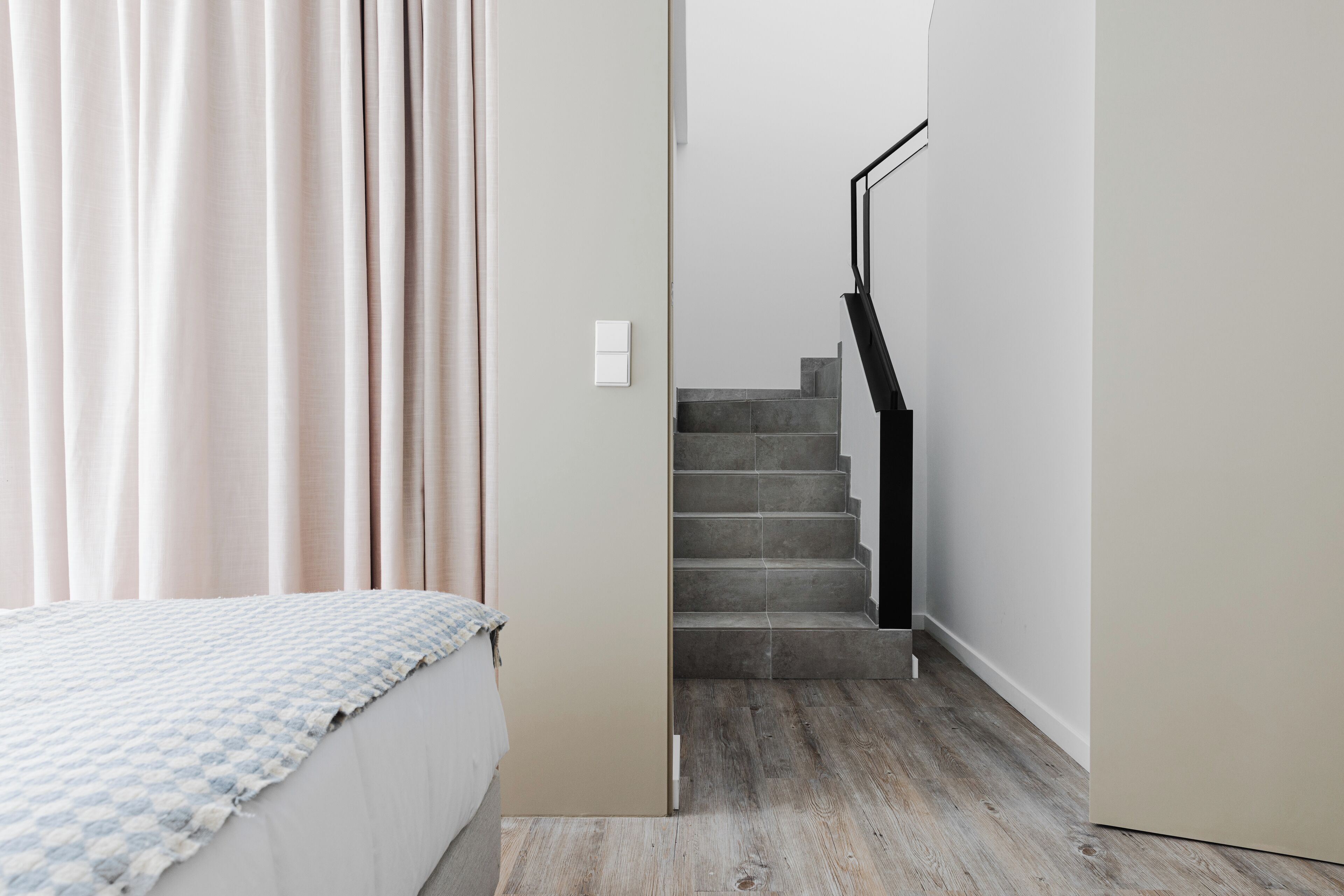 Un dormitorio con cama, una escalera y una puerta que da a otra habitación.