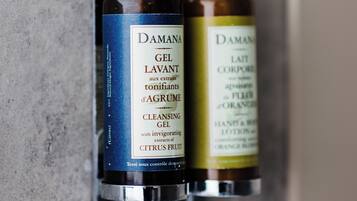 Two bottles of DAMAN GEL LAVANT and DAMAN GEL CORPORE on a bathroom wall.
