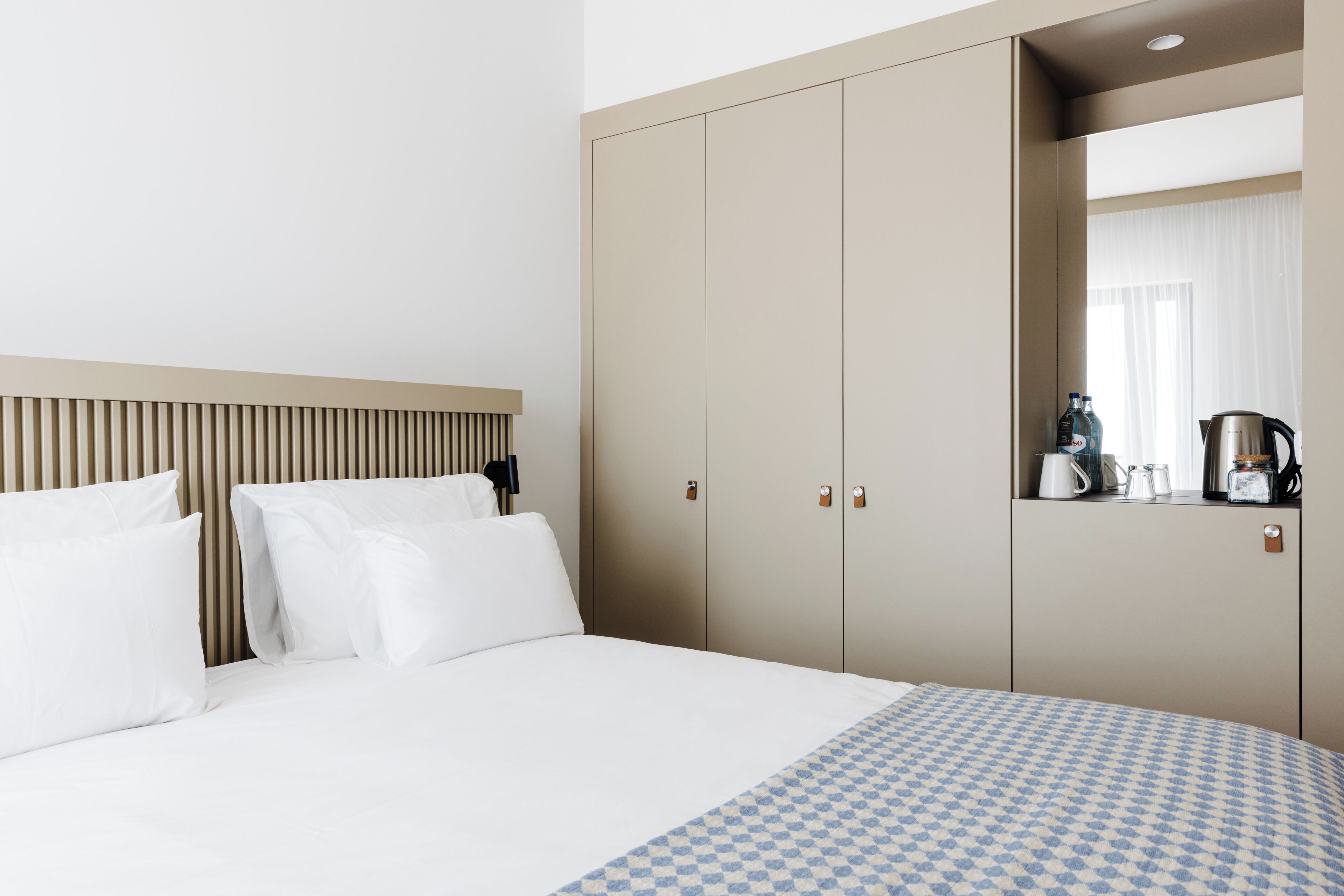 A hotel room with a bed, a wardrobe, and a mirror.