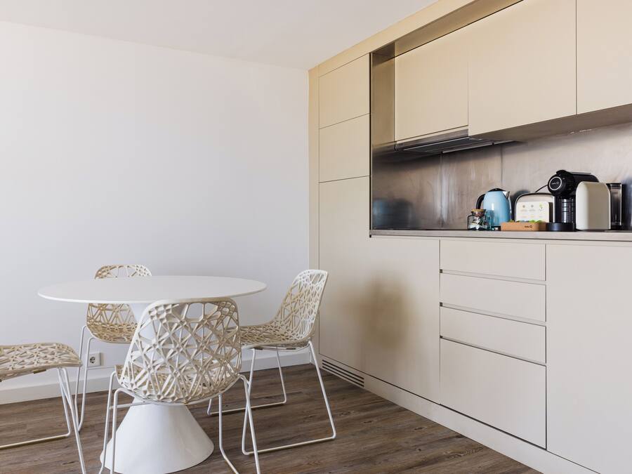 Una cocina moderna con una mesa redonda y cuatro sillas de mimbre.
