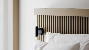 A neatly made bed with white linens and a wooden headboard with vertical slats.