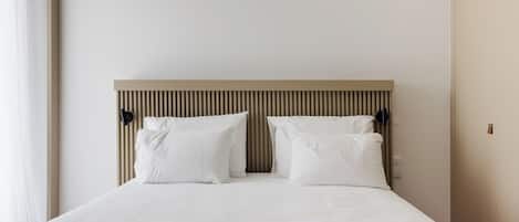 Una cama bien hecha con cabecera a rayas, dos almohadas y una colcha estampada.