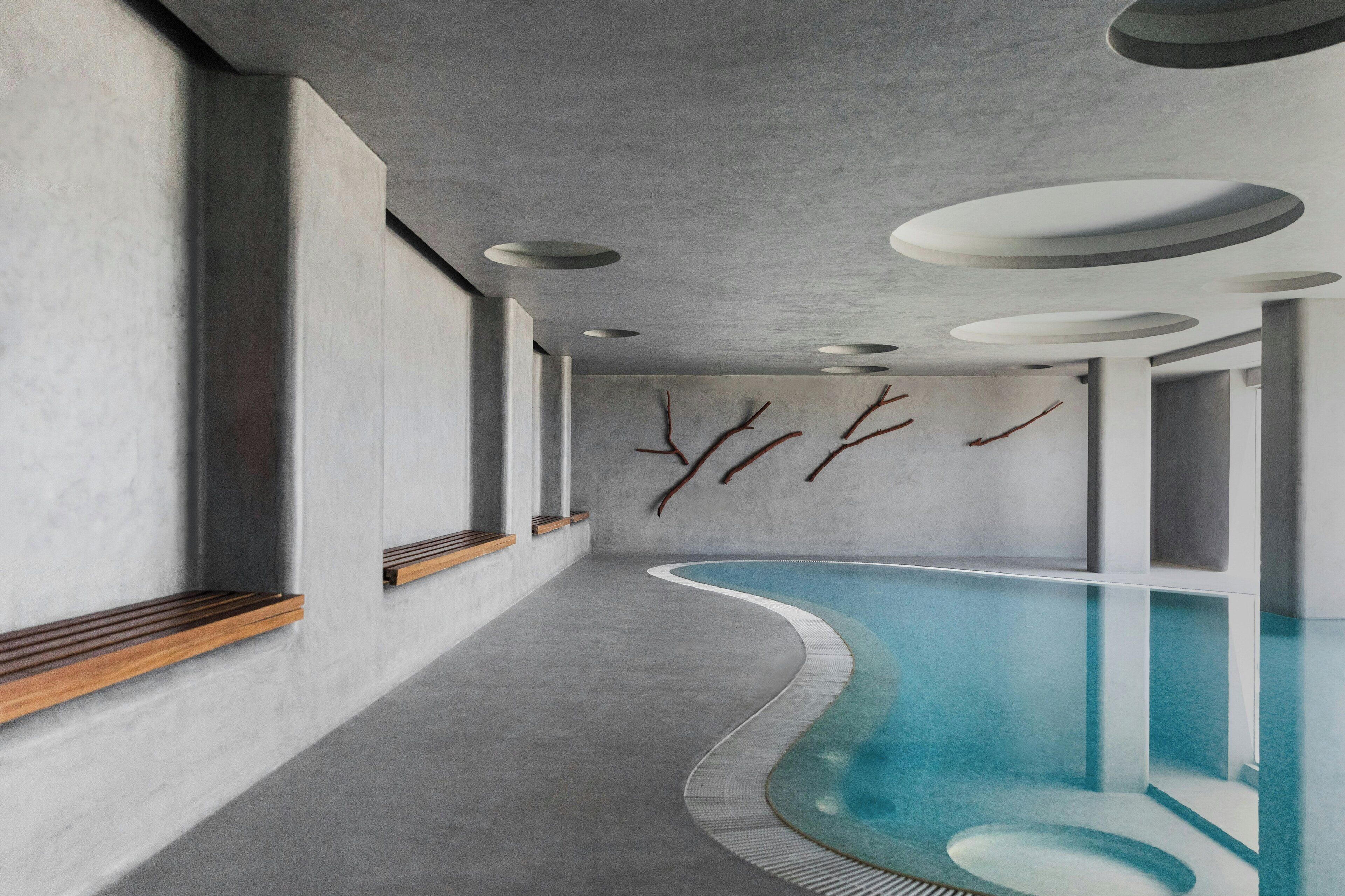 A modern indoor pool with a curved design, recessed lighting, and minimalist decor.