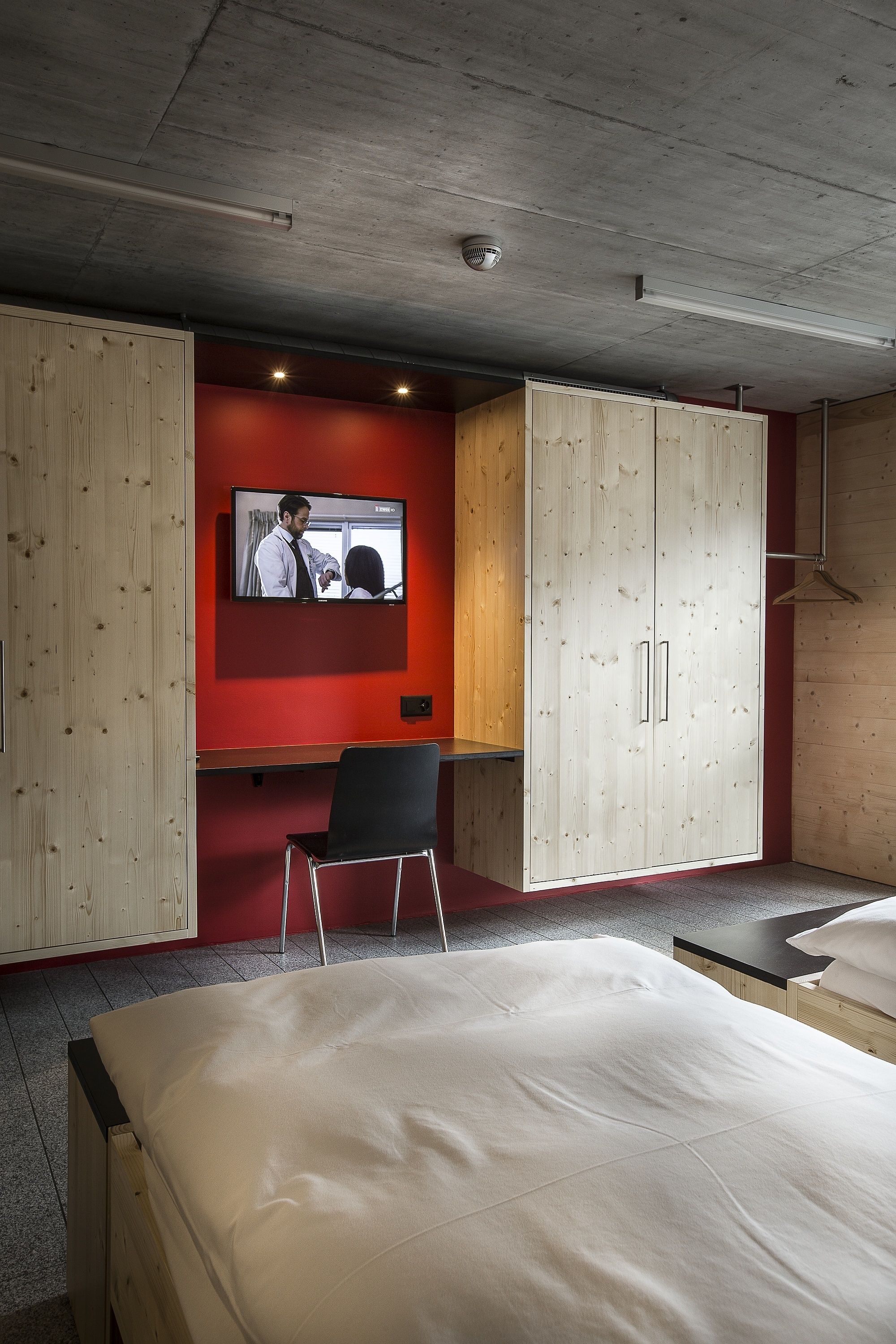Une chambre d’hôtel équipée d’un lit, d’un bureau, d’une télévision et d’armoires en bois.
