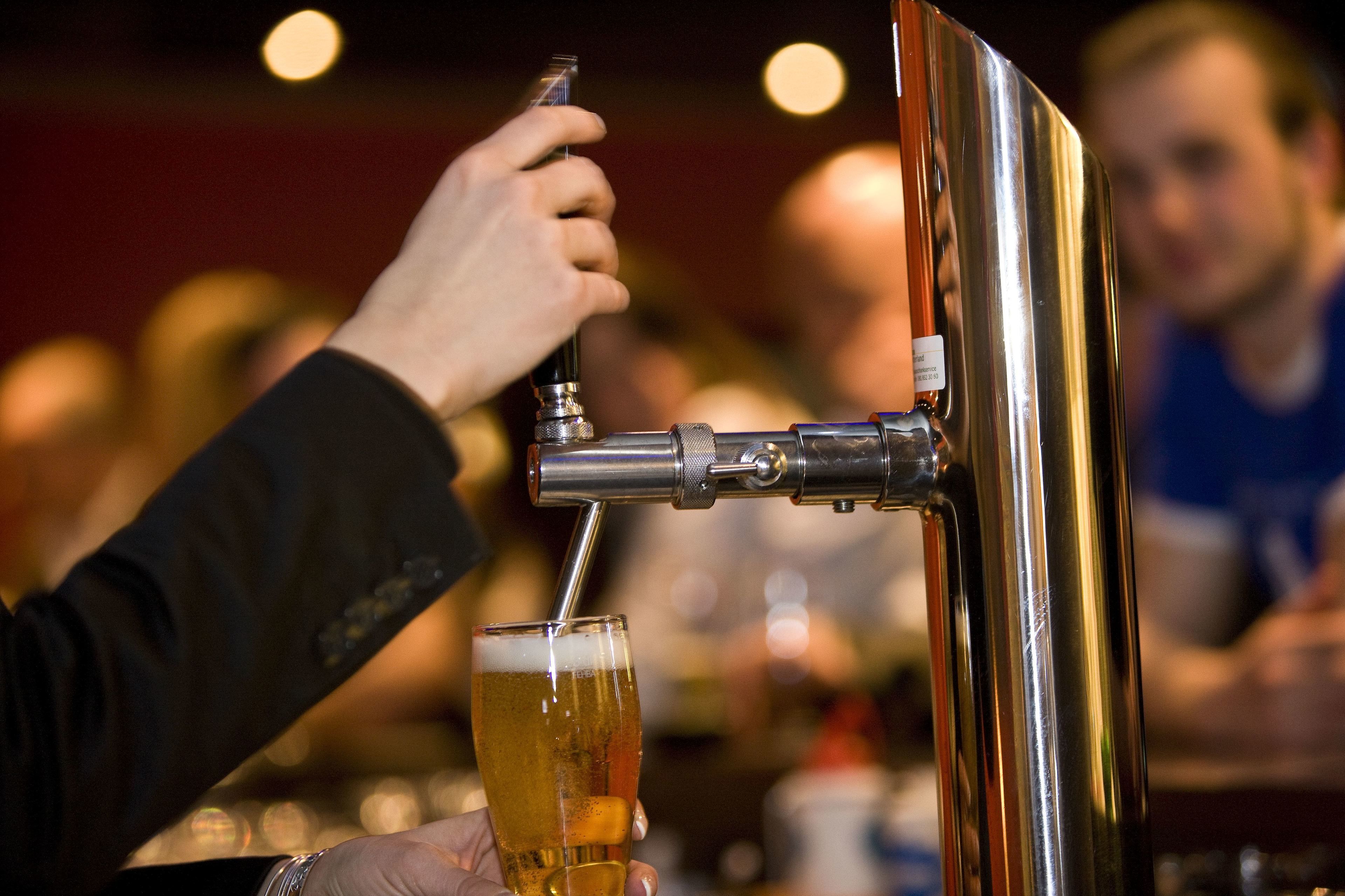 Une main tenant un verre à bière sous un robinet.