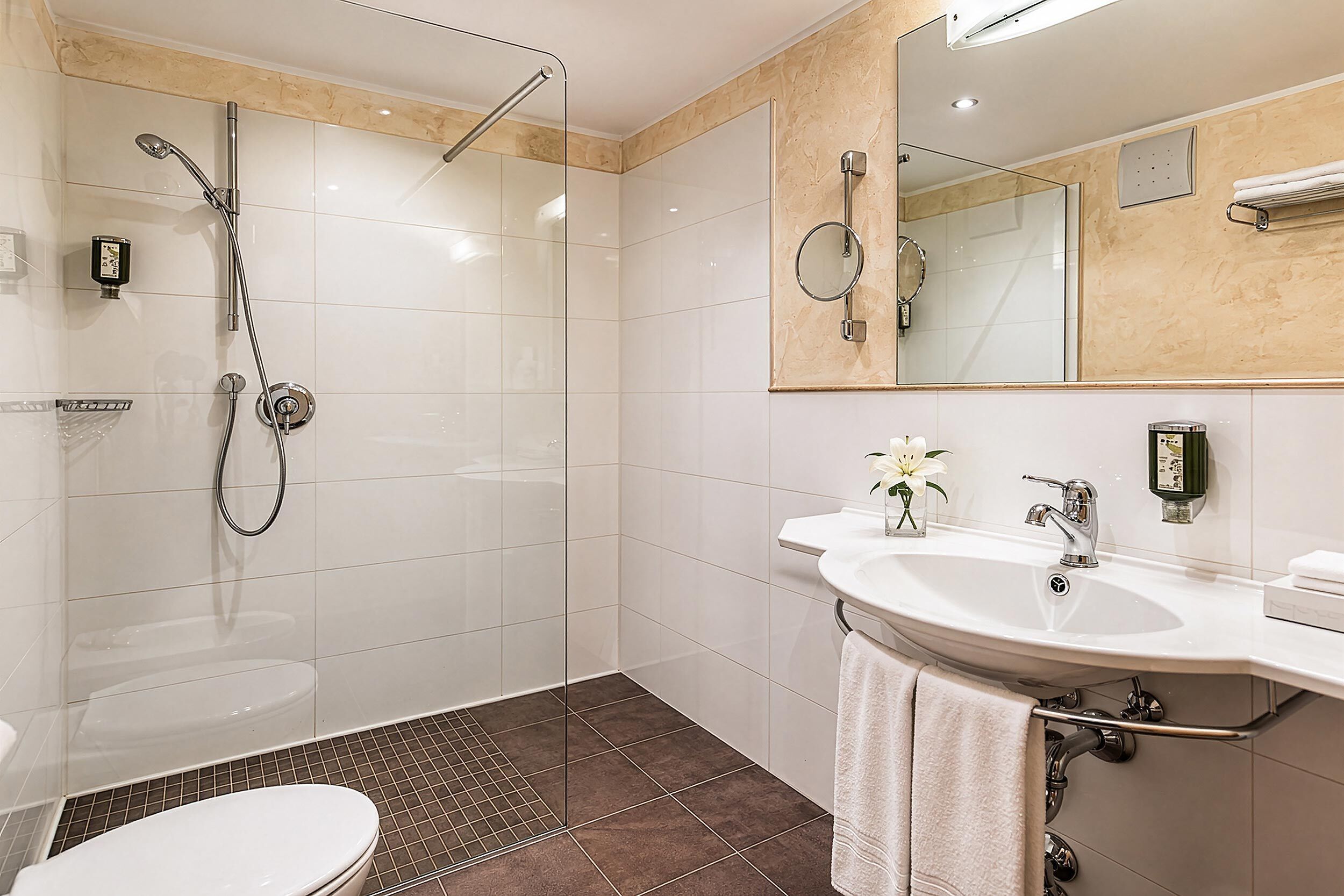 Ein modernes Badezimmer mit einer einteiligen Duschkabine, einem weißen Waschbecken mit Spiegel und einer Toilette.
