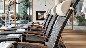 A modern lounge area with wicker chairs, a large wall clock, and a fireplace.