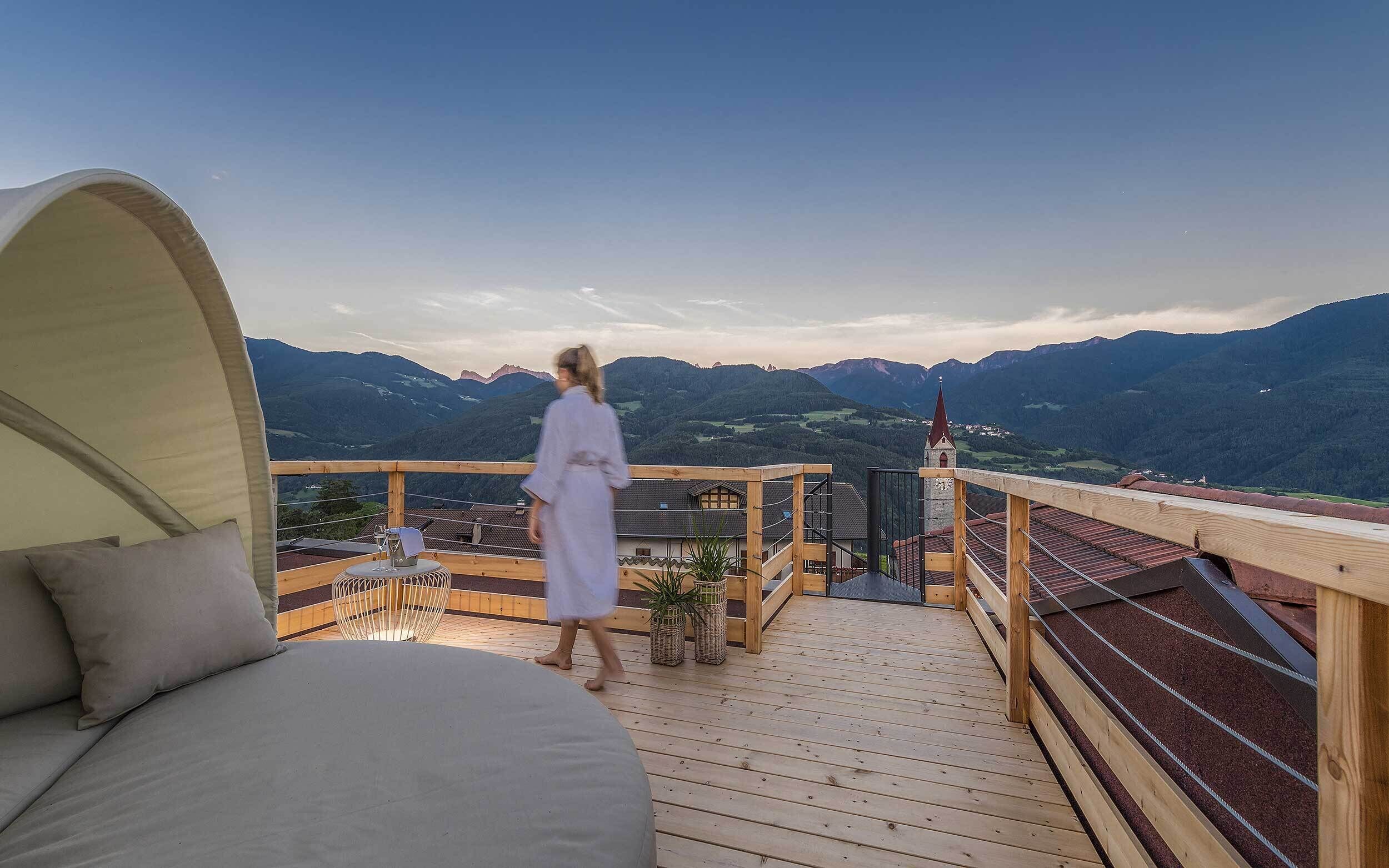 A wooden deck with a bed and a view of mountains.