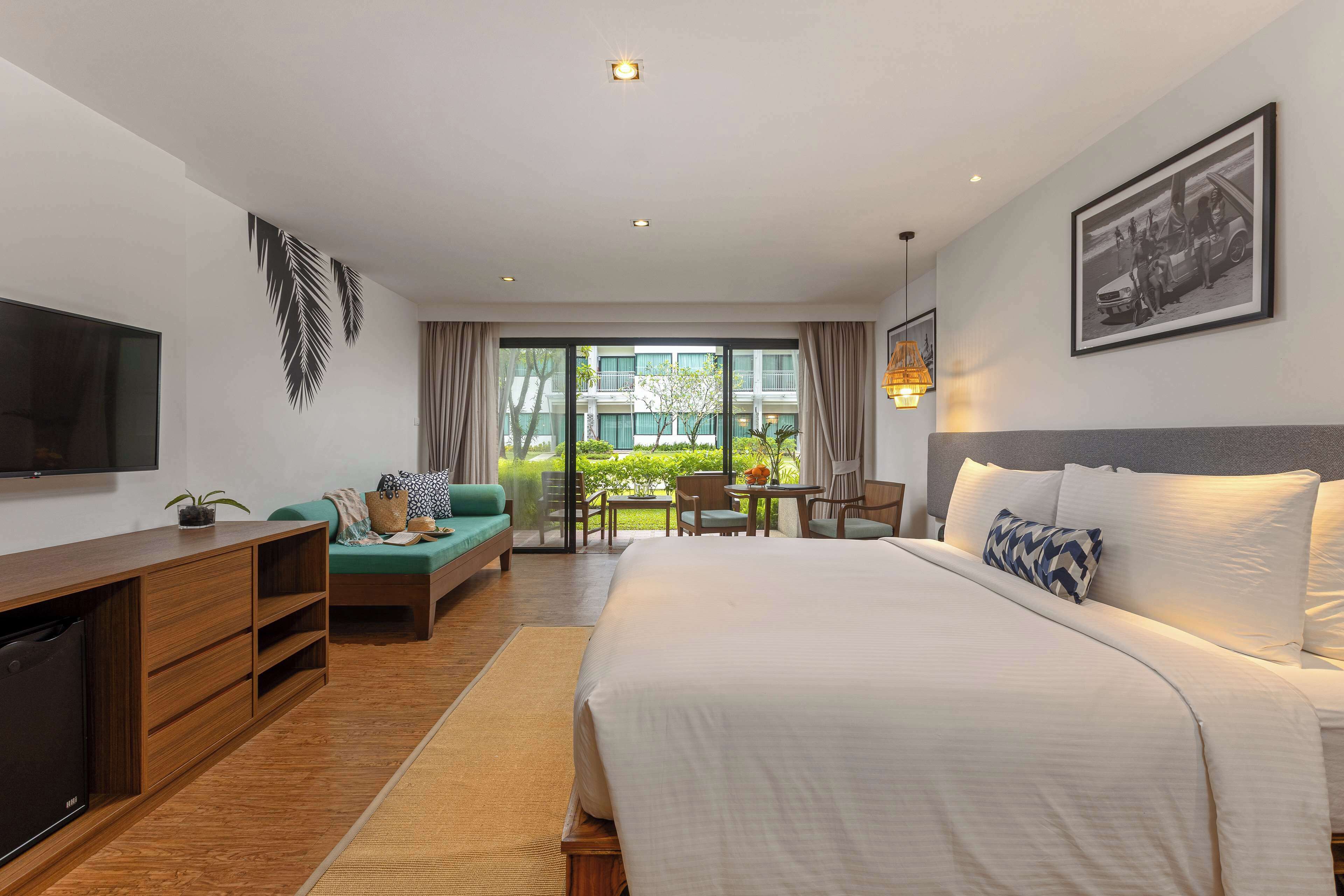 Hotelkamer met een bed, televisie, bank, bureau en een balkon met uitzicht.