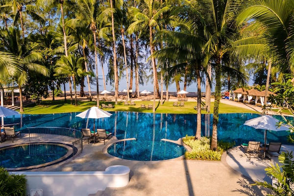 Una piscina al aire libre, sombrillas, sillones reclinables de piscina