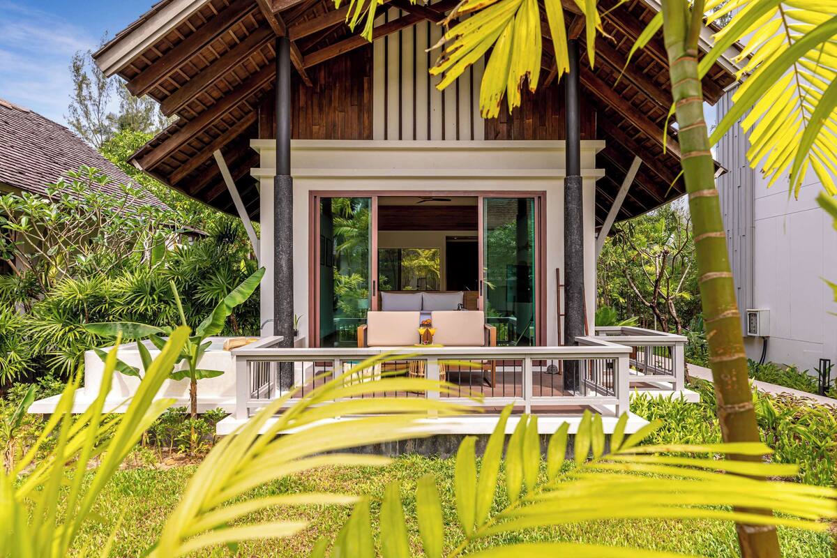 Un bâtiment moderne doté d’un toit en bois, de grandes fenêtres en verre et d’un balcon avec des sièges pour l’extérieur.