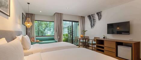 Habitación de hotel con dos camas, un escritorio con una silla, un televisor y un balcón con vistas a zonas verdes.
