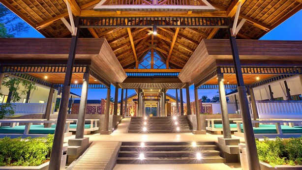 A covered outdoor area with a wooden structure, steps leading up to a central point, and seating areas.