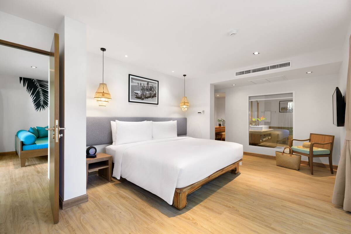 Une chambre moderne avec un grand lit, des tables de chevet, une chaise et un miroir.
