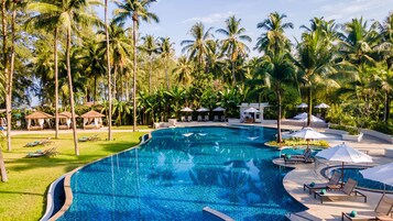 Una piscina al aire libre, sombrillas, sillones reclinables de piscina