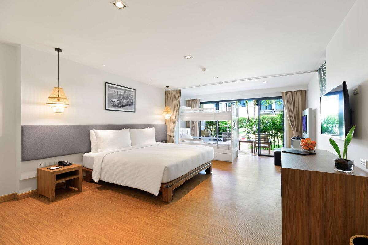 Une chambre d’hôtel moderne équipée d’un lit, d’une table de chevet, d’une lampe, d’une télévision et offrant une vue sur l’extérieur.