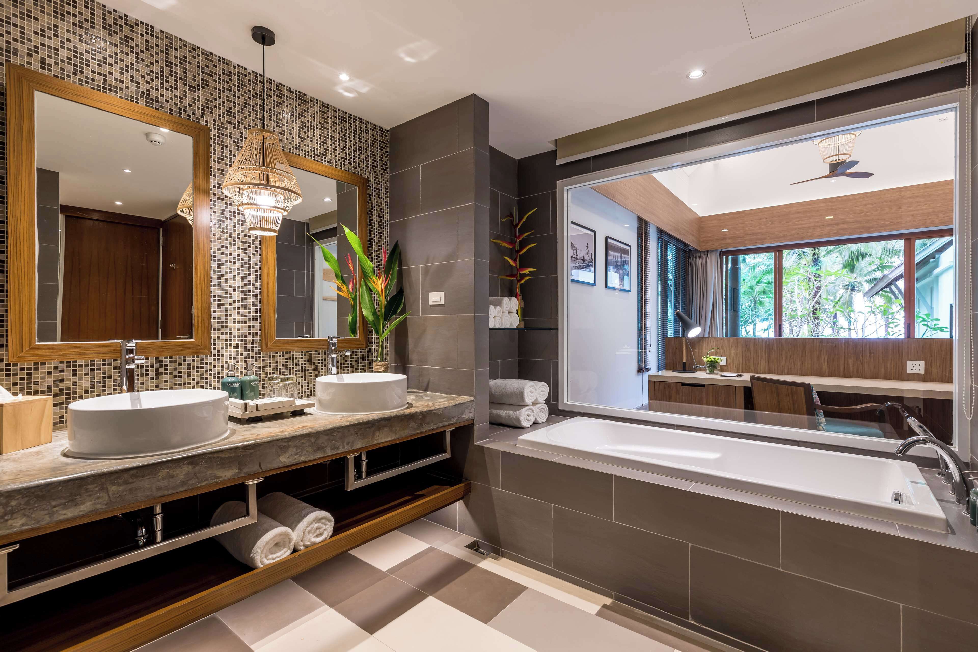Un baño moderno con dos lavamanos, una bañera grande y un espejo amplio.