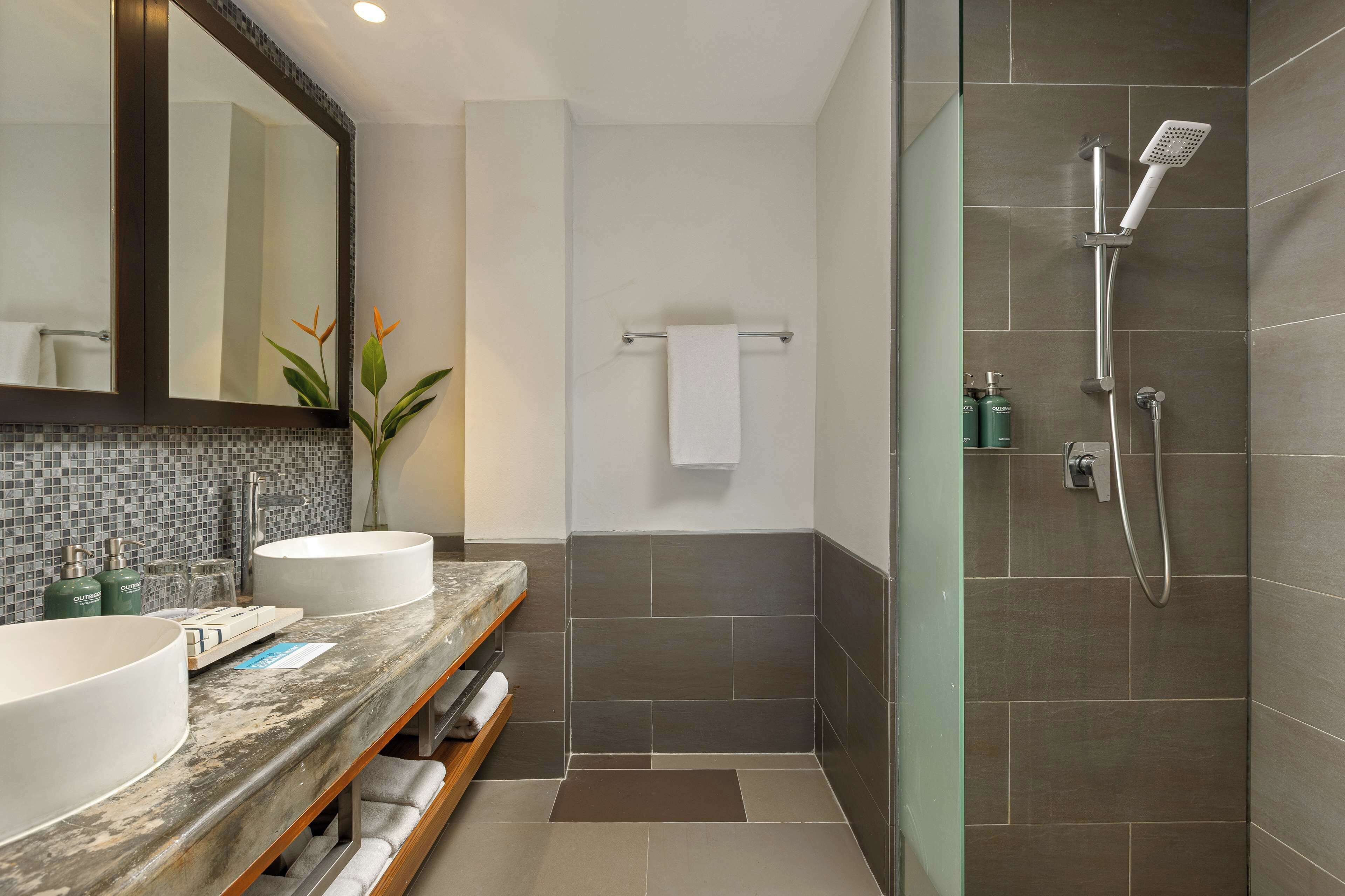 Un bagno con due lavandini, una doccia, un portasciugamani e uno specchio.