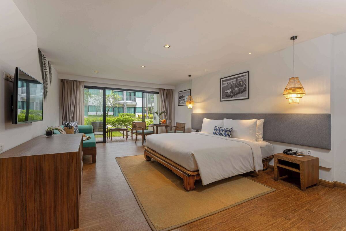 Une chambre d’hôtel comprenant un lit, une table de chevet, un bureau, une chaise et donnant sur l’extérieur.