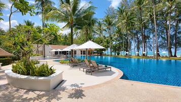 Een buitenzwembad, parasols bij het zwembad en ligstoelen
