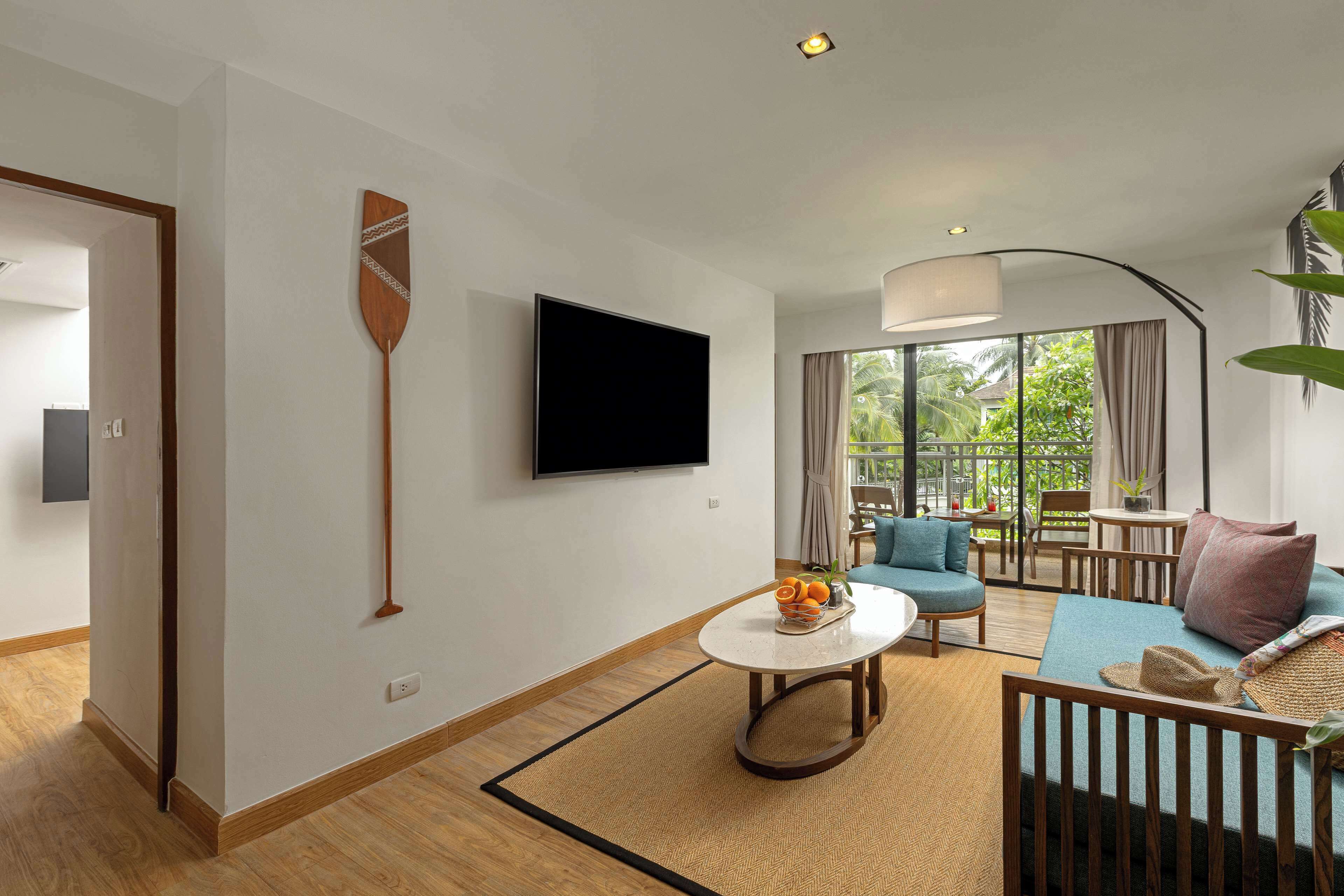 A modern living room with a flat-screen TV, a round coffee table, a sofa, and a dining area with a table and chairs.