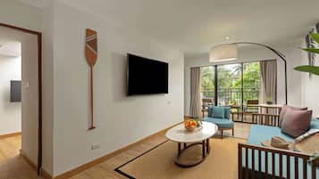 A modern living room with a flat-screen TV, a round coffee table, a sofa, and a dining area with a table and chairs.