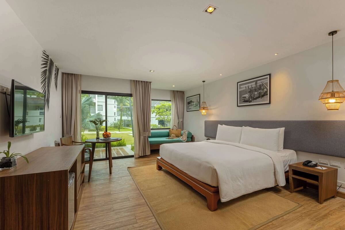 Une chambre d’hôtel équipée d’un lit, d’une table de chevet, d’un bureau et offrant une vue sur l’extérieur.