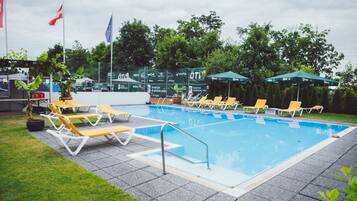 Una piscina al aire libre de temporada, sombrillas, tumbonas