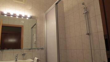 Un baño con lavamanos, espejo y ducha.