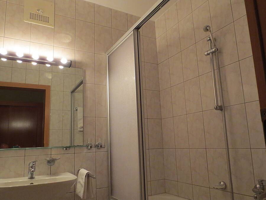 Un baño con lavamanos, espejo y ducha.