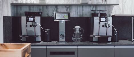 Una estación de café con dos máquinas de espresso, un dispensador de agua y una pantalla digital con el menú de café.