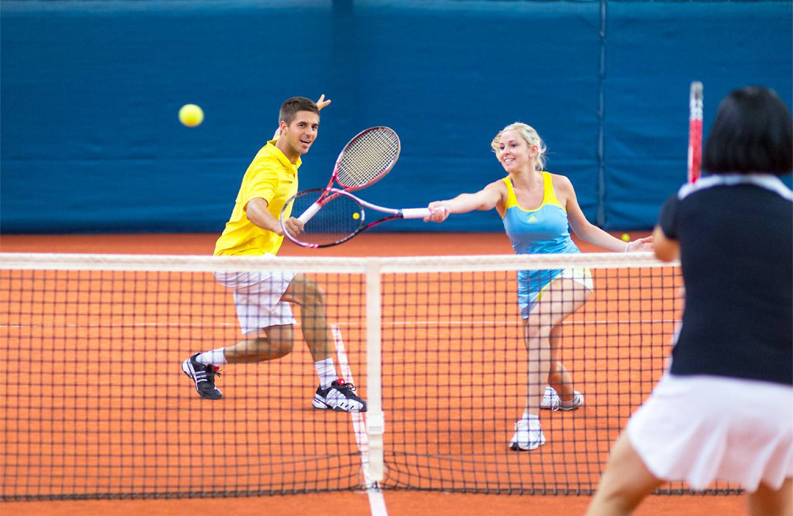 Un court de tennis où les joueurs portent des tenues jaunes et bleues.