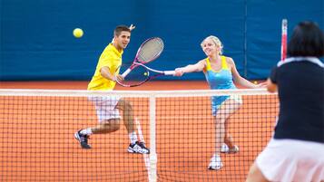 Un court de tennis où les joueurs portent des tenues jaunes et bleues.