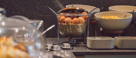 A buffet setup with various food items and a bowl of eggs.