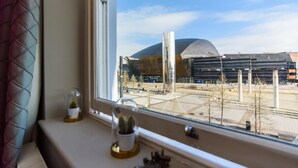 A window view of a modern building with a dome structure, a clear sky, and a few trees. - Jolyon's Boutique Hotel (Cardiff)